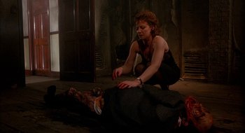 Movie still from “Hellraiser” (1987), directed by Clive Barker – A woman in a black top is putting a bag on a dead body; Medium shot, Low angle