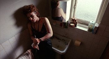 Movie still from “Hellraiser” (1987), directed by Clive Barker – A woman in a black top is in a bathroom; Medium shot, High angle