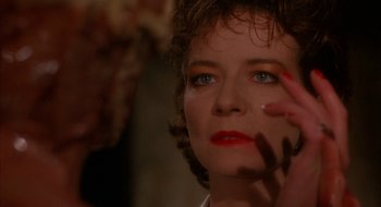 Movie still from “Hellraiser” (1987), directed by Clive Barker – A person with red lipstick on their face; Close Up shot, Over the shoulder angle