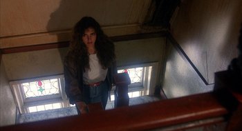 Movie still from “Hellraiser” (1987), directed by Clive Barker – A woman standing on the stairs looking at the camera; Medium shot, Low angle