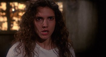 Movie still from “Hellraiser” (1987), directed by Clive Barker – A woman with long curly brown hair stares into the camera; Close Up shot, Over the shoulder angle