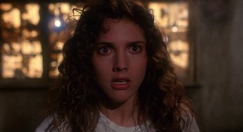 Movie still from “Hellraiser” (1987), directed by Clive Barker – A woman with curly brown hair stares into the camera; Close Up shot, Over the shoulder angle