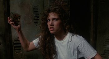 Movie still from “Hellraiser” (1987), directed by Clive Barker – A woman with long curly brown hair wearing a white t - shirt; Close Up shot, Over the shoulder angle