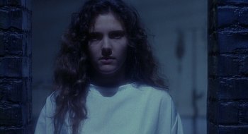 Movie still from “Hellraiser” (1987), directed by Clive Barker – A woman with long curly hair standing in a dark room; Close Up shot, Low angle