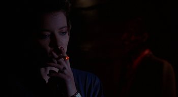 Movie still from “Hellraiser” (1987), directed by Clive Barker – A woman smoking a cigarette in a dark room; Close Up shot, Over the shoulder angle