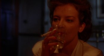 Movie still from “Hellraiser” (1987), directed by Clive Barker – A woman drinking a glass of water while smoking a cigarette; Close Up shot, Low angle