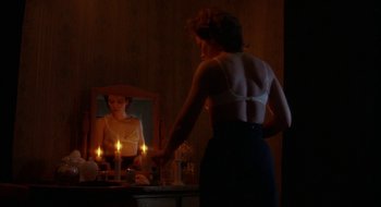 Movie still from “Hellraiser” (1987), directed by Clive Barker – A woman standing in front of a mirror looking in the mirror; Medium shot, Over the shoulder angle