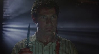 Movie still from “Hellraiser” (1987), directed by Clive Barker – A person holding a knife in his hand; Close Up shot, Low angle