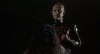 Movie still from “Hellraiser” (1987), directed by Clive Barker – A man in a black suit and a woman in a white dress; Medium shot, Low angle