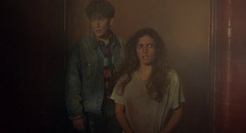 Movie still from “Hellraiser” (1987), directed by Clive Barker – A man and a woman standing next to each other; Medium shot, High angle