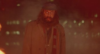 Movie still from “Hellraiser” (1987), directed by Clive Barker – A man with long hair and a beard wearing a hat and a scarf; Close Up shot, Over the shoulder angle