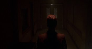 Movie still from “Hellraiser III: Hell on Earth” (1992), directed by Anthony Hickox – A person standing in a dark room looking at a door; Wide shot, Low angle