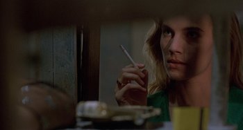 Movie still from “Hellraiser III: Hell on Earth” (1992), directed by Anthony Hickox – A woman sitting at a table with a cigarette in her hand; Close Up shot, Over the shoulder angle