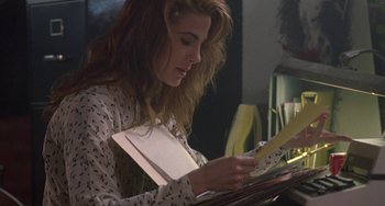 Movie still from “Hellraiser III: Hell on Earth” (1992), directed by Anthony Hickox – A woman sitting at a table looking down at a piece of paper; Medium shot, Over the shoulder angle