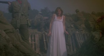 A woman in a long white dress standing in front of soldiers