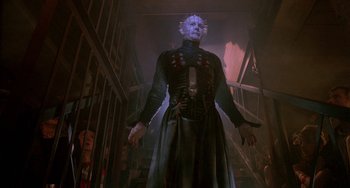 Movie still from “Hellraiser III: Hell on Earth” (1992), directed by Anthony Hickox – A man in a black dress standing in a dark room; Medium shot, Low angle
