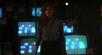 Movie still from “Hellraiser III: Hell on Earth” (1992), directed by Anthony Hickox – A woman standing in front of a bunch of tv screens; Medium shot, Low angle