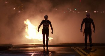 Movie still from “Hellraiser III: Hell on Earth” (1992), directed by Anthony Hickox – A person in a helmet standing in front of a fire at night; Medium shot, Low angle