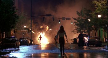 Movie still from “Hellraiser III: Hell on Earth” (1992), directed by Anthony Hickox – A woman walking down a street near a fire; Extreme Wide shot, Over the shoulder angle
