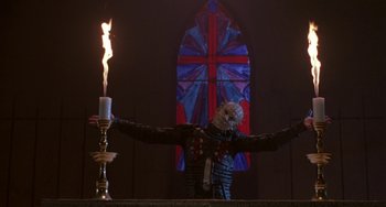 Movie still from “Hellraiser III: Hell on Earth” (1992), directed by Anthony Hickox – A candle is lit in front of a stained glass window; Medium shot, Low angle