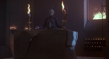 Movie still from “Hellraiser III: Hell on Earth” (1992), directed by Anthony Hickox – A man in a leather jacket standing in front of lit candles; Wide shot, Low angle