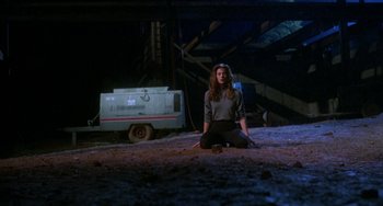 Movie still from “Hellraiser III: Hell on Earth” (1992), directed by Anthony Hickox – A woman sitting on the ground in front of a trailer; Wide shot, High angle