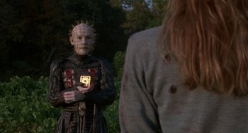 Movie still from “Hellraiser III: Hell on Earth” (1992), directed by Anthony Hickox – A man with a face like a pinhead holding a cell phone; Medium shot, Over the shoulder angle