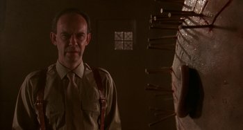 Movie still from “Hellraiser III: Hell on Earth” (1992), directed by Anthony Hickox – A man standing in front of a bunch of wooden poles; Close Up shot, Low angle