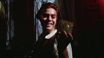 Movie still from “Hellraiser: Bloodline” (1996), directed by Kevin Yagher – A young man holding up an old book in front of a window; Close Up shot, Low angle