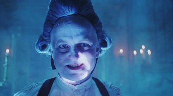 Movie still from “Hellraiser: Bloodline” (1996), directed by Kevin Yagher – An old woman with blue hair is smiling for the camera; Close Up shot, Low angle