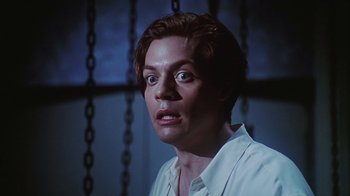 Movie still from “Hellraiser: Bloodline” (1996), directed by Kevin Yagher – A person wearing a white shirt with chains in the background; Close Up shot, Low angle