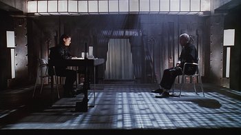 Movie still from “Hellraiser: Bloodline” (1996), directed by Kevin Yagher – Two people sitting at a table in a dimly - lit room; Wide shot, High angle