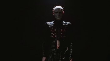 Movie still from “Hellraiser: Bloodline” (1996), directed by Kevin Yagher – A person in a black costume with red spikes on his head; Medium shot, Low angle