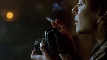 Movie still from “Hellraiser: Deader” (2005), directed by Rick Bota – A woman is holding a camera and smoking a cigarette; Extreme Close Up shot, Low angle