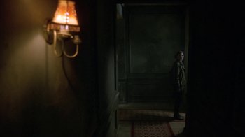 Movie still from “Hellraiser: Deader” (2005), directed by Rick Bota – A man standing in a dark room next to a lamp; Wide shot, Low angle