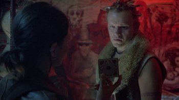 Movie still from “Hellraiser: Deader” (2005), directed by Rick Bota – A person holding a box in front of another person in a room; Close Up shot, Over the shoulder angle