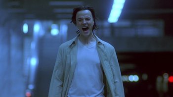 Movie still from “Hellraiser: Deader” (2005), directed by Rick Bota – A man with long black hair and a white t - shirt is laughing; Close Up shot, Low angle