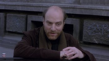 Movie still from “Hellraiser: Deader” (2005), directed by Rick Bota – A man with a beard is sitting outside; Close Up shot, High angle