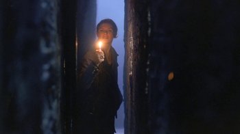 Movie still from “Hellraiser: Deader” (2005), directed by Rick Bota – A woman holding a candle in a dark room; Medium shot, Low angle