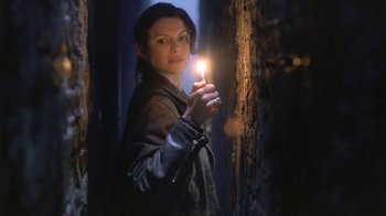 Movie still from “Hellraiser: Deader” (2005), directed by Rick Bota – A woman holding a lit candle in a dark room; Medium shot, Low angle