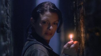 Movie still from “Hellraiser: Deader” (2005), directed by Rick Bota – A woman holding a lit candle in a dark room; Close Up shot, High angle