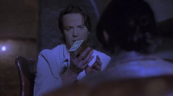 Movie still from “Hellraiser: Deader” (2005), directed by Rick Bota – A man holding a piece of food in front of a mirror; Close Up shot, Over the shoulder angle