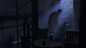 Movie still from “Hellraiser: Deader” (2005), directed by Rick Bota – A man in a lab coat shaking hands with another man in a dark room; Wide shot, Low angle