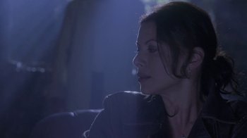 Movie still from “Hellraiser: Deader” (2005), directed by Rick Bota – A woman sitting in a dark room with her head turned to the side; Close Up shot, Over the shoulder angle
