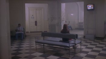 Movie still from “Hellraiser: Deader” (2005), directed by Rick Bota – A person sitting on a bench in a room; Wide shot, High angle