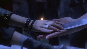 Movie still from “Hellraiser: Deader” (2005), directed by Rick Bota – Two people holding hands with a candle in the background; Extreme Close Up shot, Overhead angle