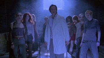 Movie still from “Hellraiser: Deader” (2005), directed by Rick Bota – A group of people standing around a man in a lab coat; Medium shot, Low angle