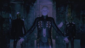 Movie still from “Hellraiser: Deader” (2005), directed by Rick Bota – A man in a costume stands next to a wall; Medium shot, Low angle