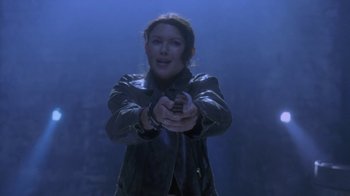 Movie still from “Hellraiser: Deader” (2005), directed by Rick Bota – A woman in a leather jacket holding a gun in her hand; Medium shot, Low angle
