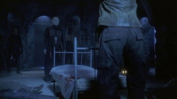 A person standing next to a bed in a dark room